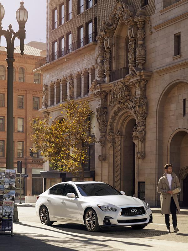 A white INFINITI Q50 parked on a city street.