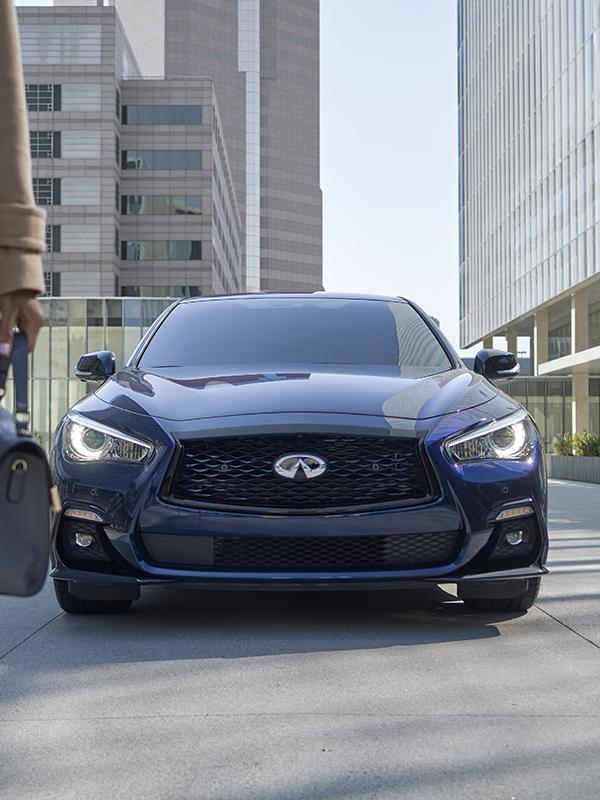 Head-on view of a blue INFINITI Q50 parked on a city street.