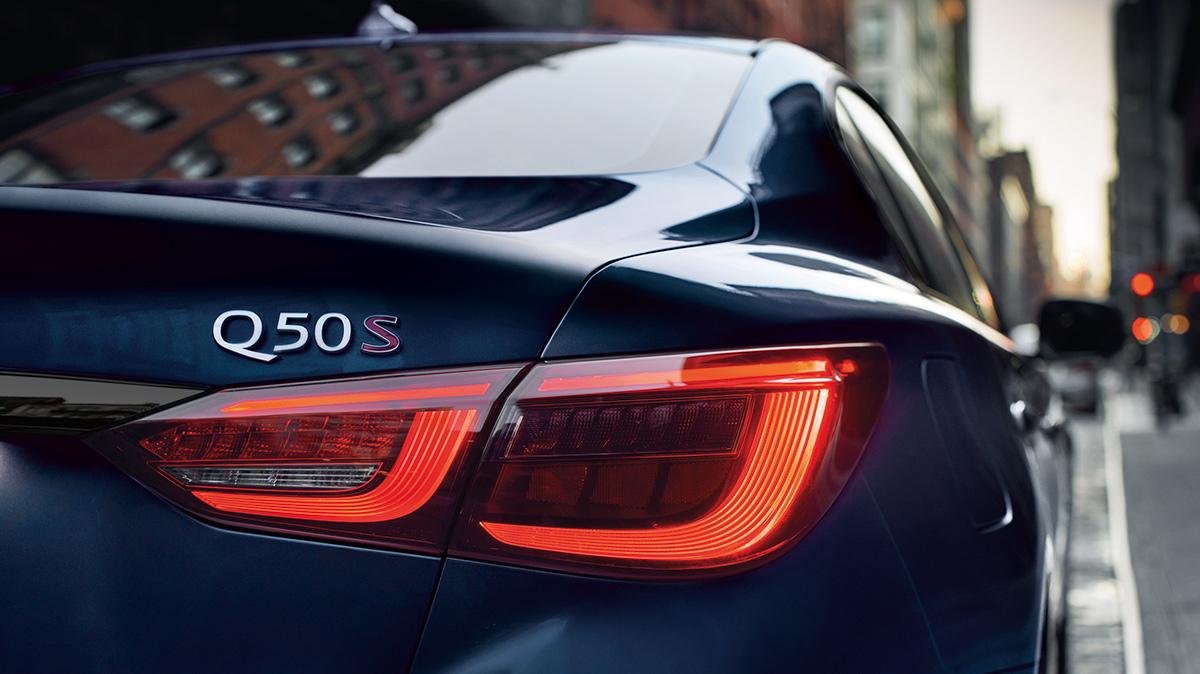 Close-up view of the taillight of a blue Q50 in the city.