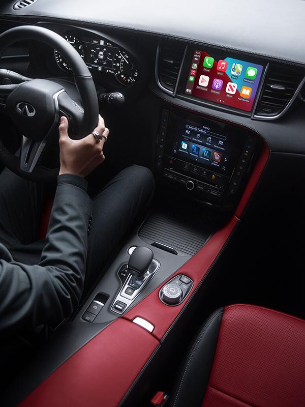 High angle interior view of an INFINITI QX55 center console featuring red and dark grey upholstery.