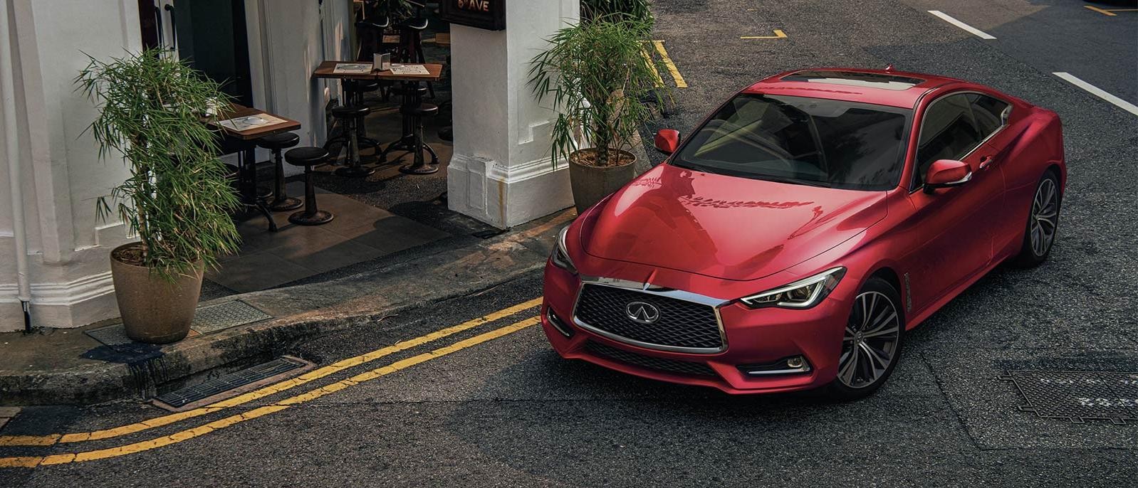 Red INFINITI Q60 parked on a street in front of a cafe