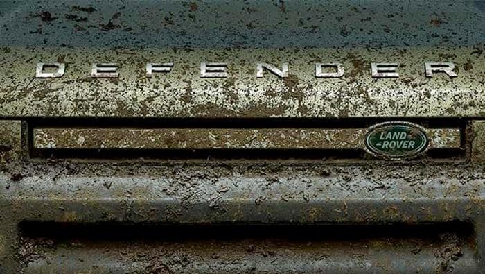 Close-up of the muddy front grille of a Land Rover Defender.