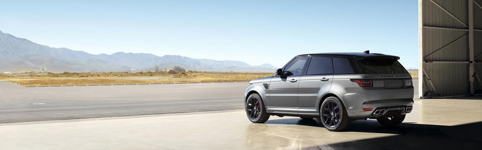 A silver Range Rover Sport parked in a desert airplane hangar.