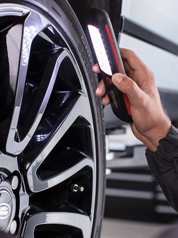 Land Rover technician inspecting wheels and brakes.