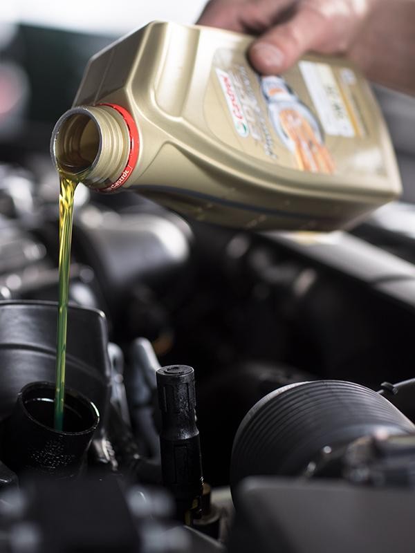 Close up of a Land Rover technician changing the oil on a vehicle.