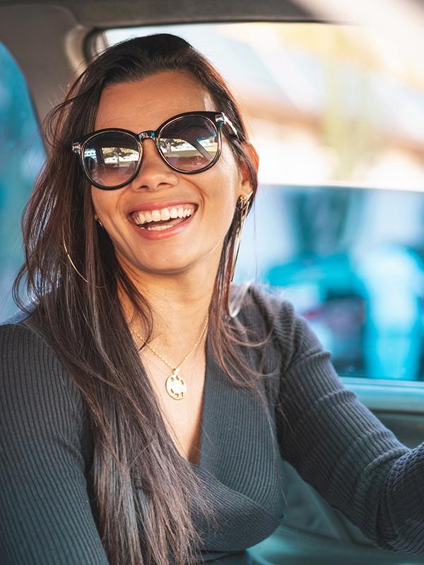 A smiling woman sitting in the driver's seat of a car.