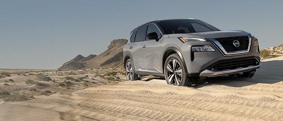 A grey Nissan Rogue driving off-road in the desert.