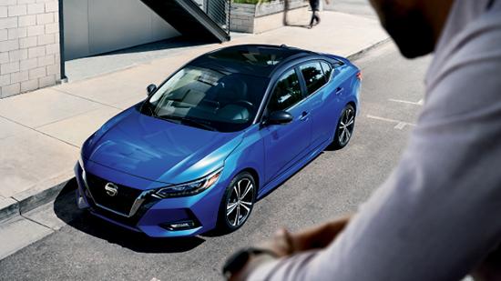 Man looking at Blue Nissan parked on street