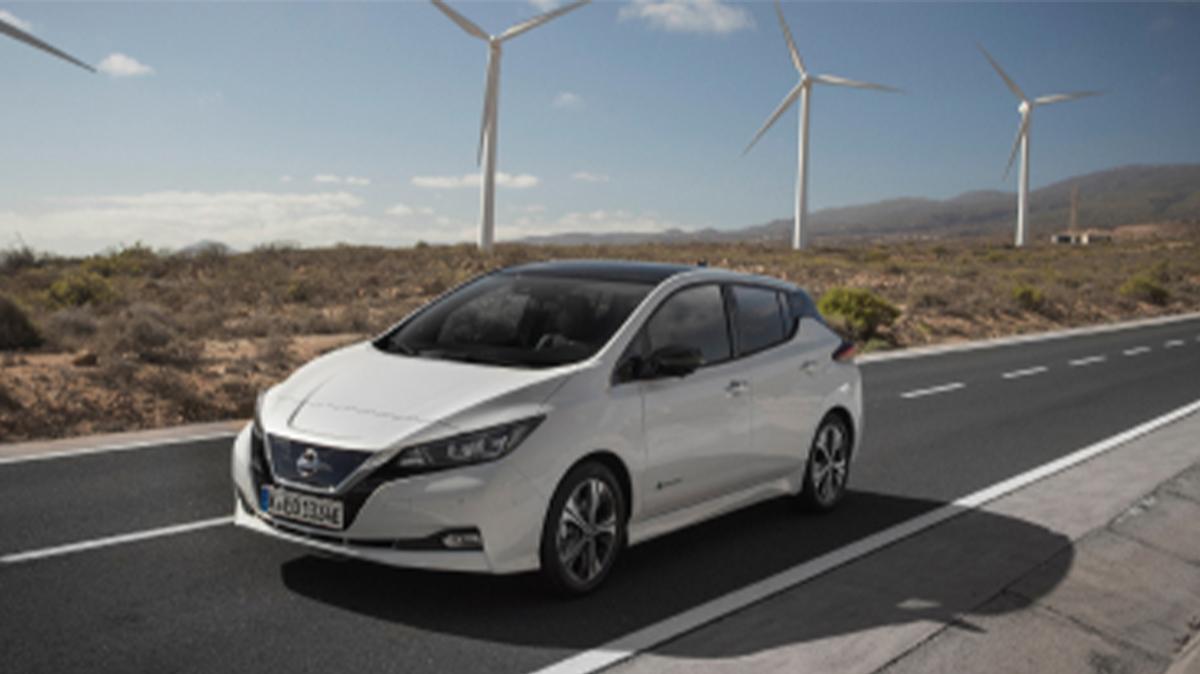 Nissan vehicle driving on road, wind turbines in the background