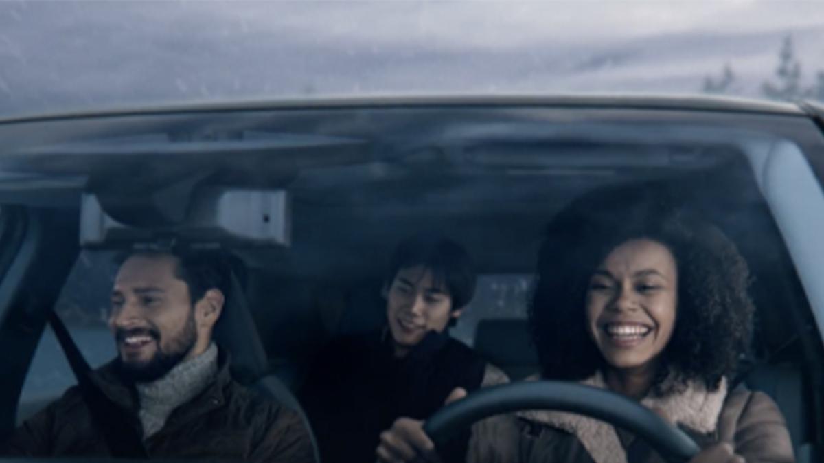 Three passengers riding in a vehicle and smiling