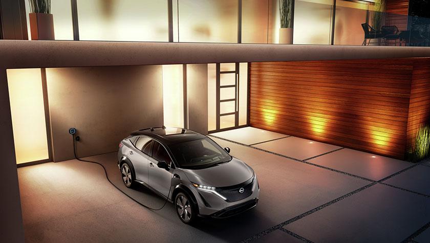 Nissan ARIYA plugged-in and charging outside a home