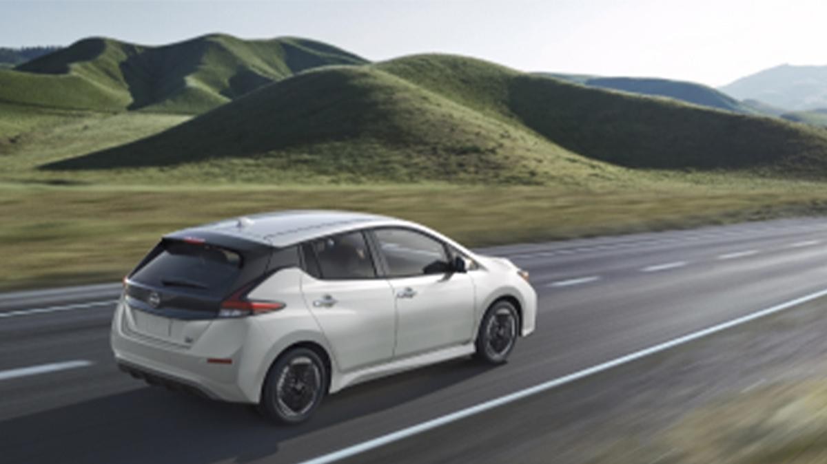 Nissan EV on the road with green hills in the background