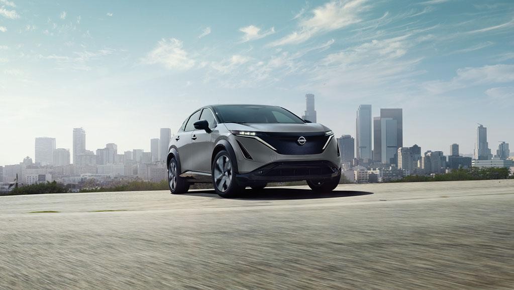 Side view of Nissan ARIYA in front of a building.