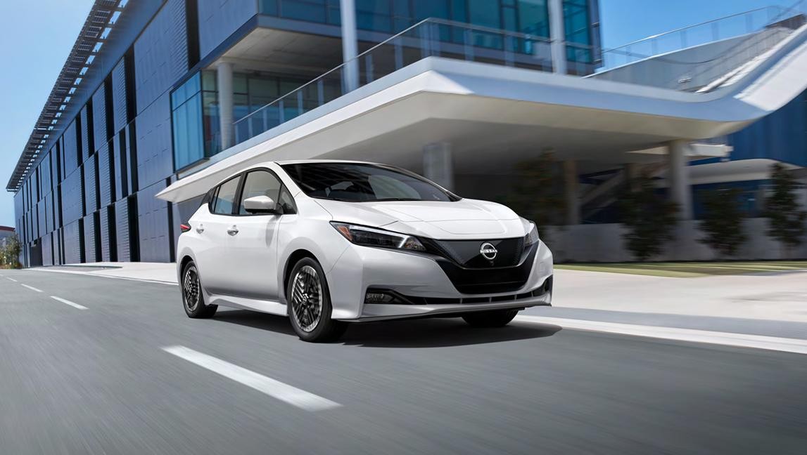 Nissan LEAF front view driving on road in front of building.