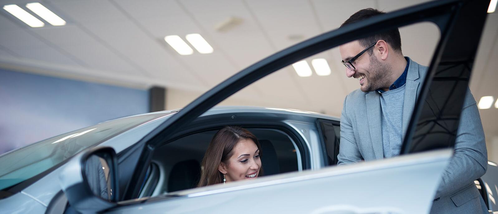 Dealership sales associate showing a customer a new vehicle