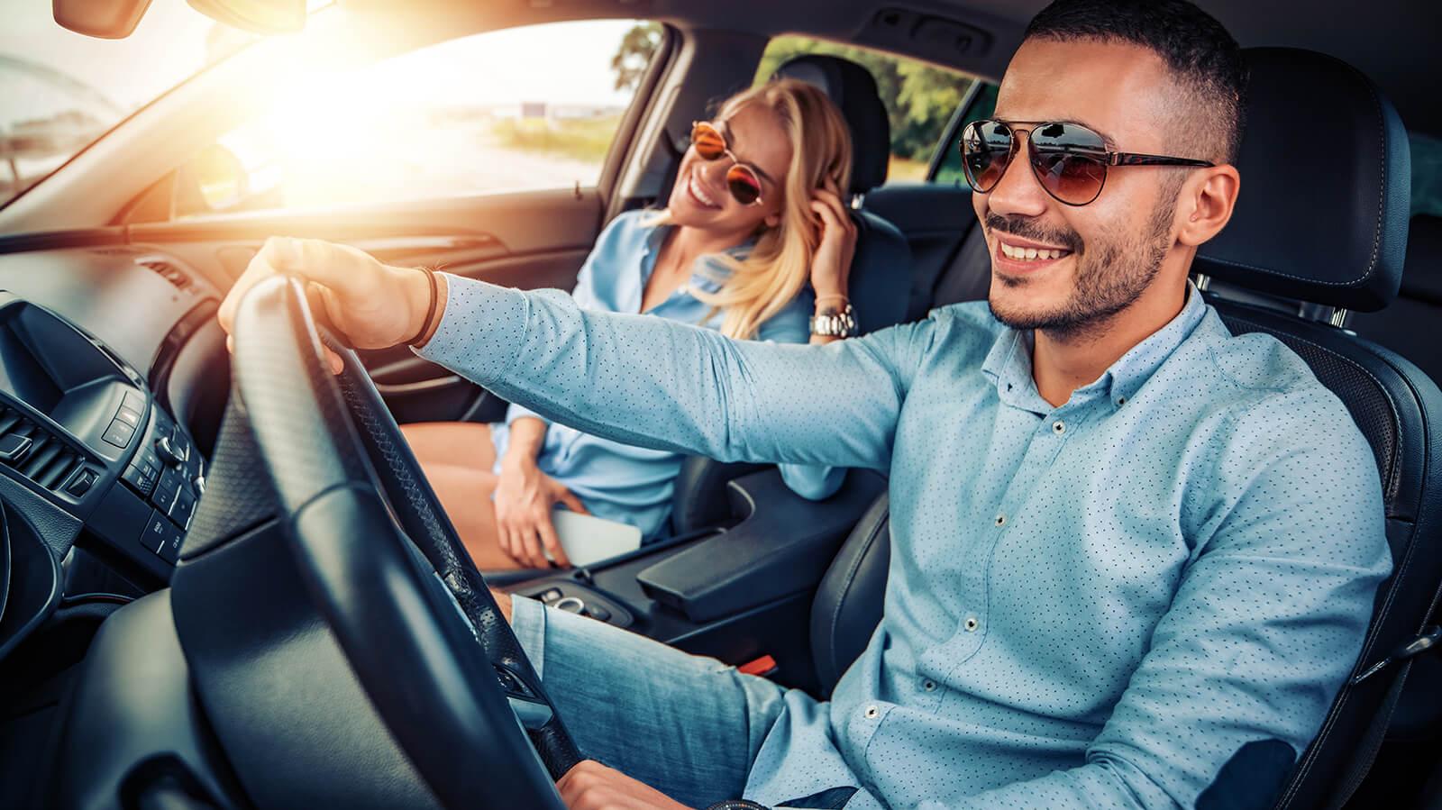 Happy couple wearing sunglasses while driving in a car