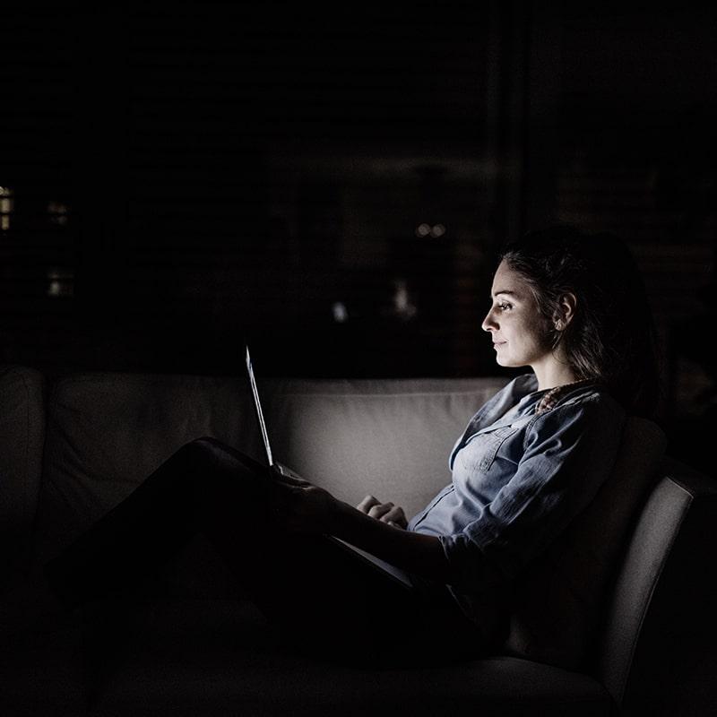Woman at night using her laptop computer on the couch