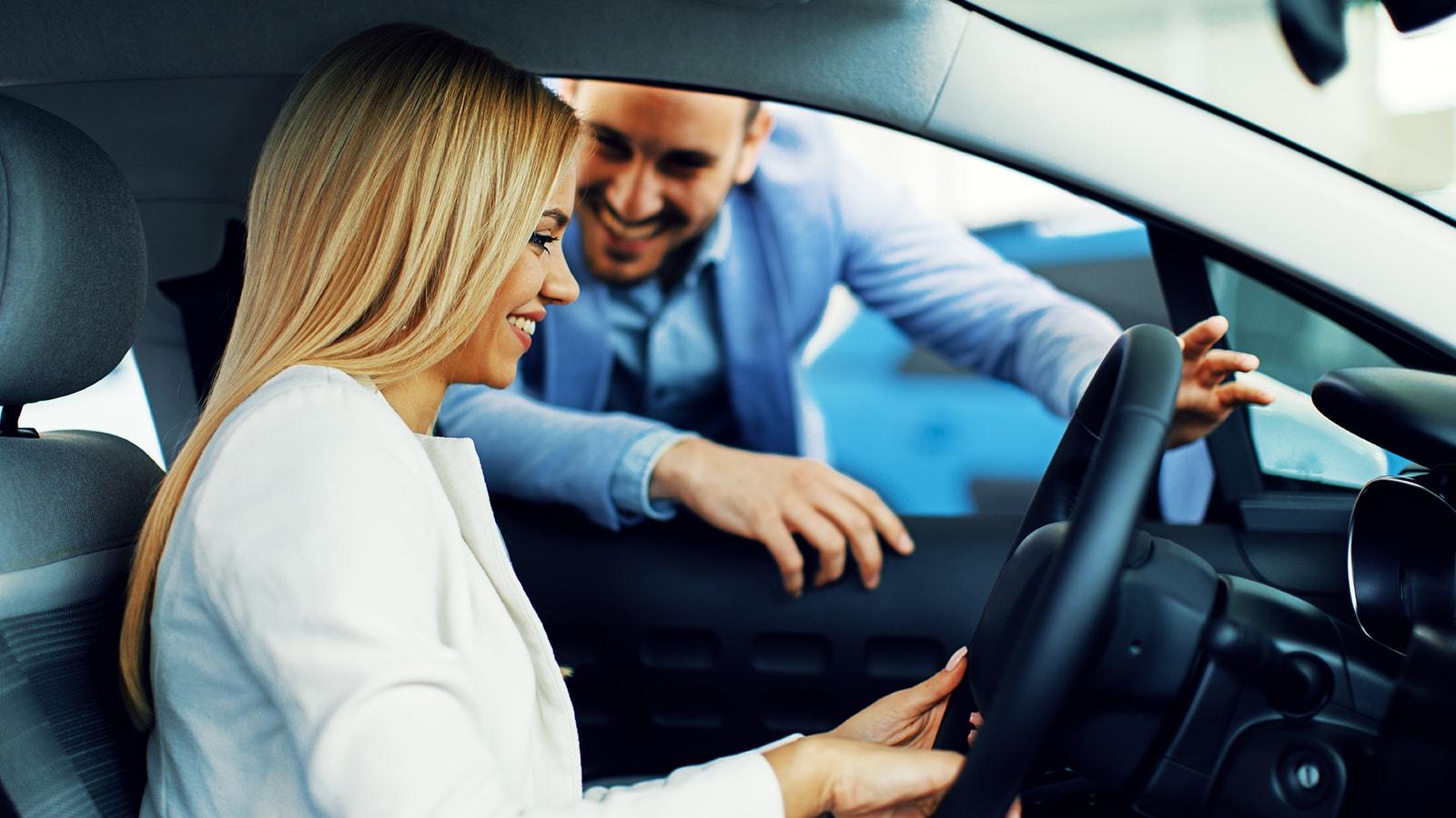 Smiling woman in a dealership sitting in a new vehicle