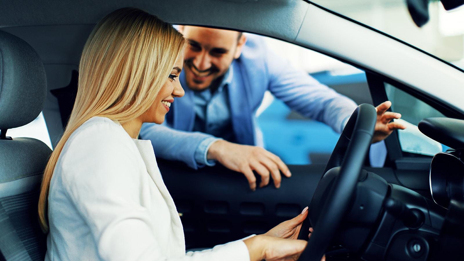 Smiling woman in a dealership sitting in a new vehicle