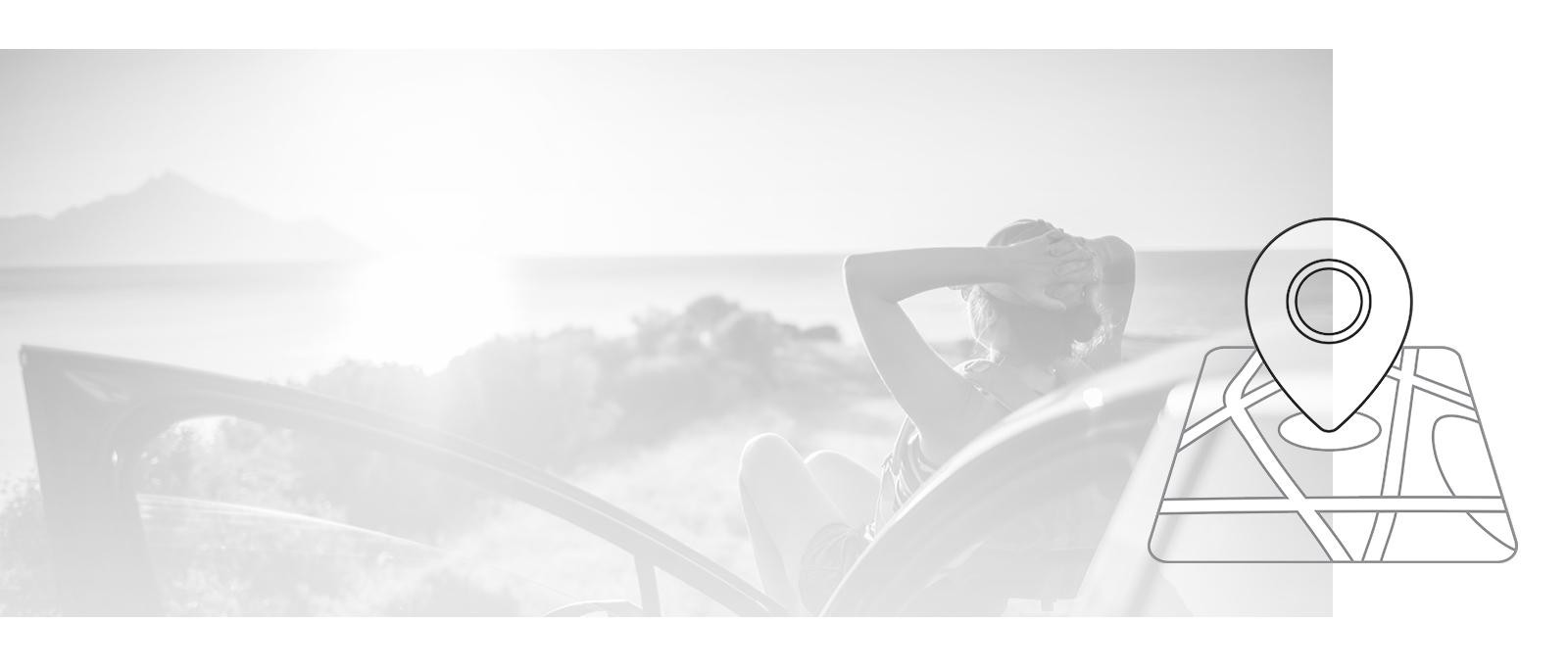 Woman sitting on the hood of her car watching the sunset over the water