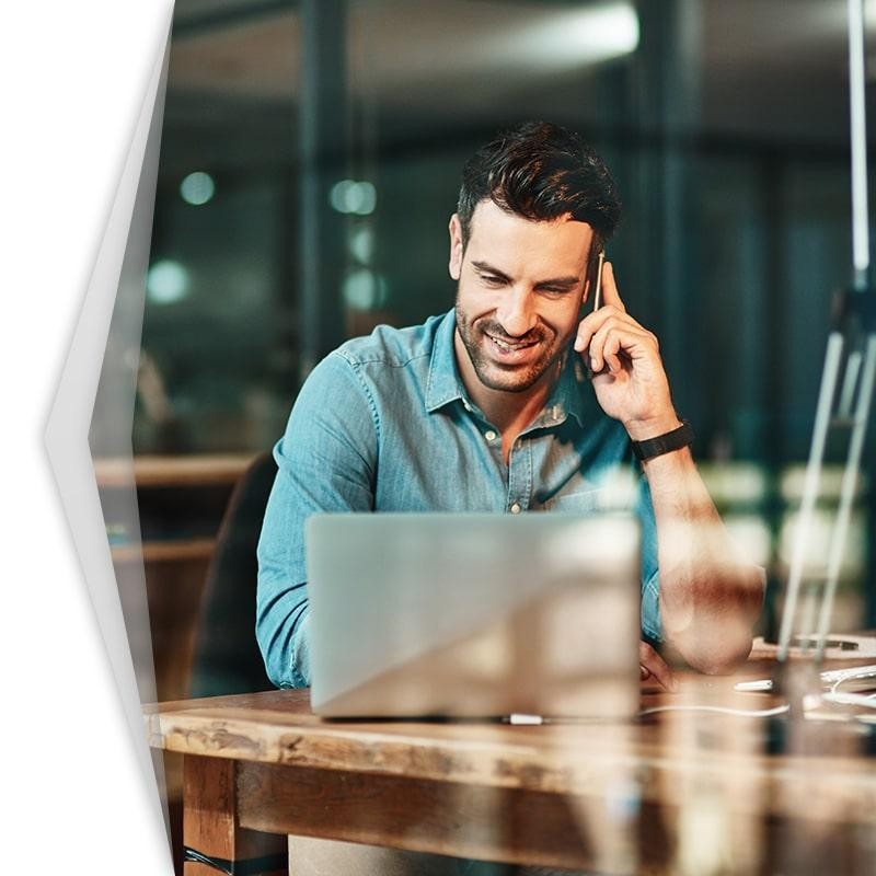 Man using a phone while looking at a laptop