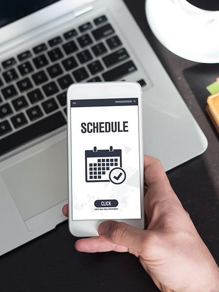 Hand holding a smart phone with a schedule service icon