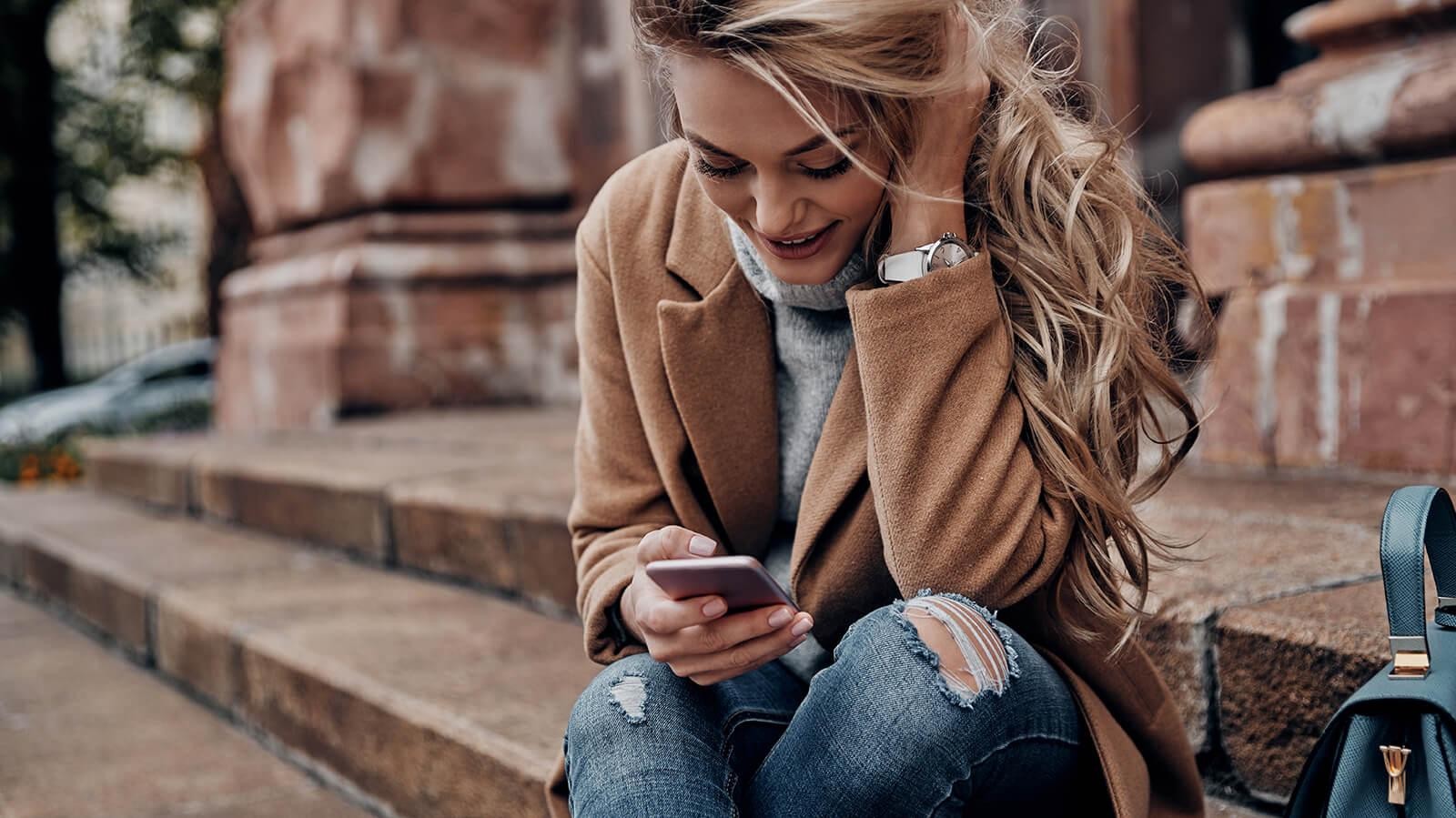 Woman sitting on some steps while looking at her phone