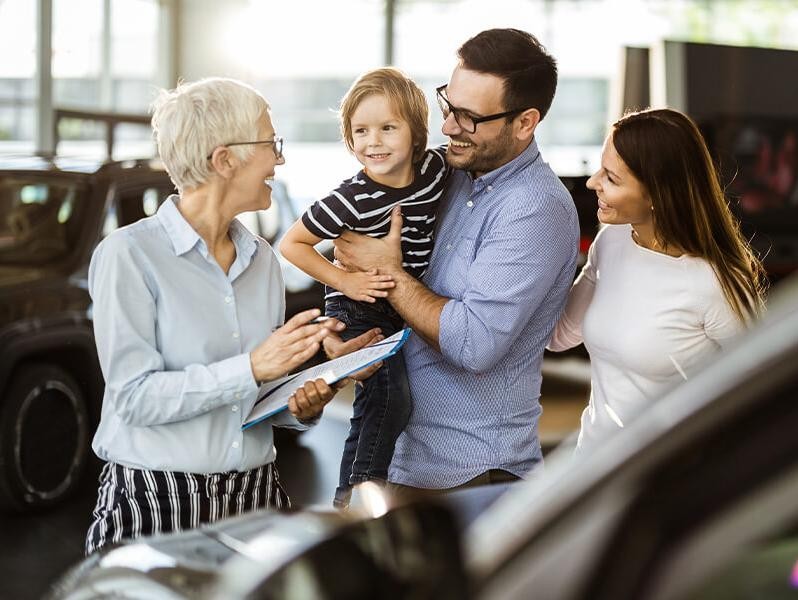 Young family in a dealership vehicle showroom