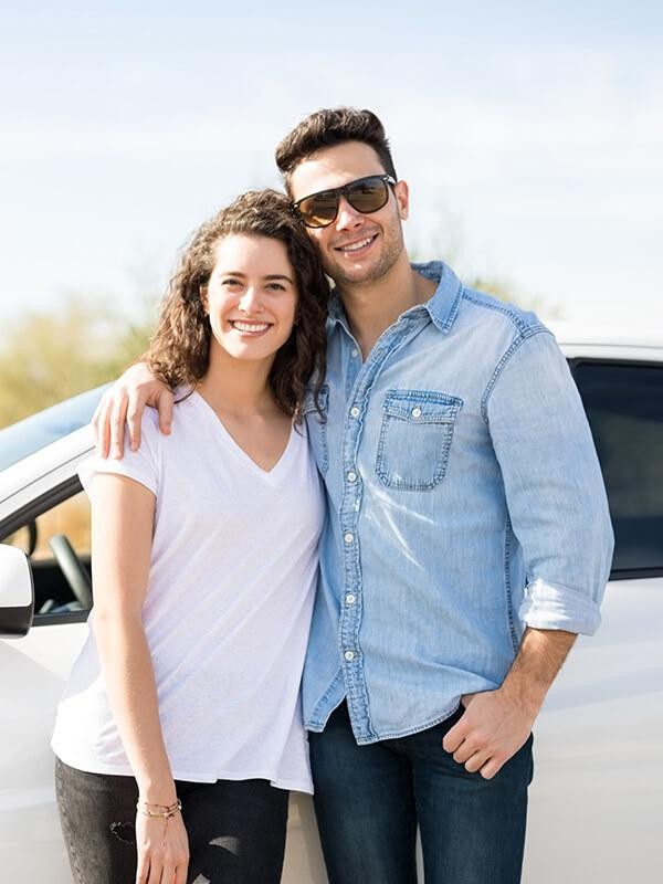 Smiling couple in front of their new car