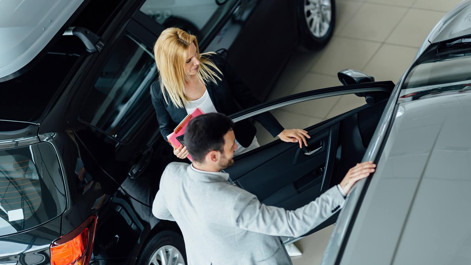 Dealership sales associate showing a customer a new car