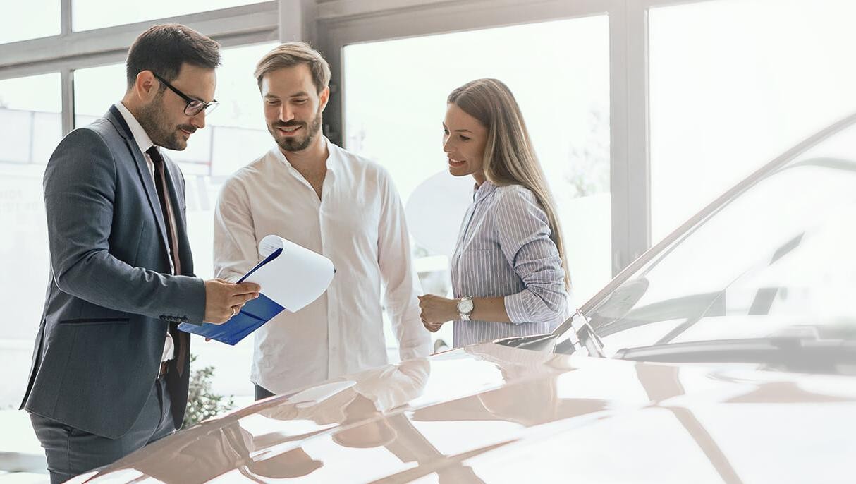 Dealership sales associate helping a smiling couple shop for a new vehicle