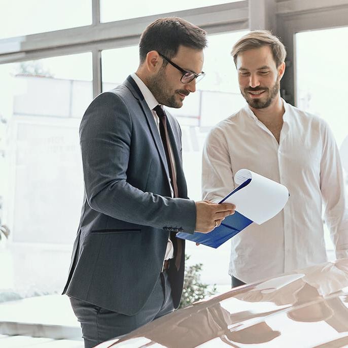 Dealership sales associate helping a smiling couple shop for a new vehicle