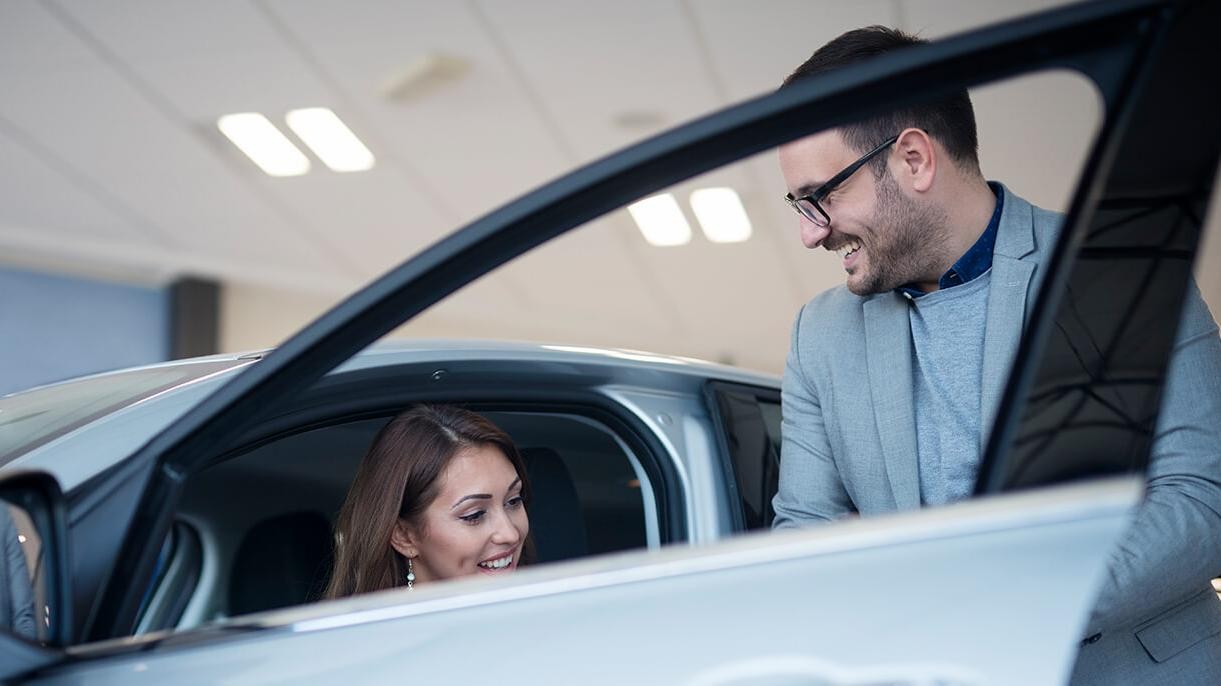 Dealership sales associate showing a customer a new vehicle