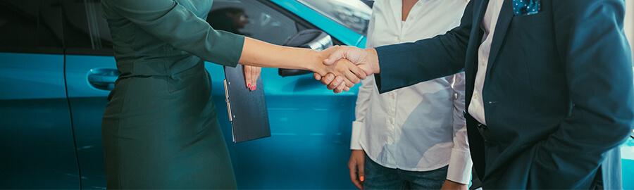 Woman shaking hands with customers in a dealership