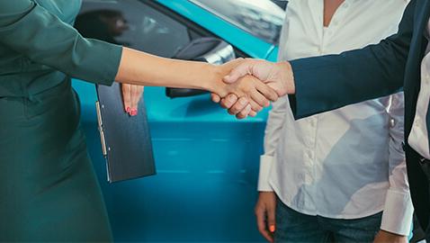 Woman shaking hands with customers in a dealership