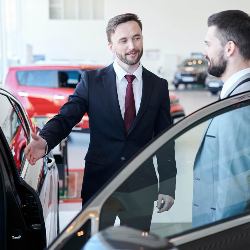 Dealership sales associate showing a customer a new vehicle