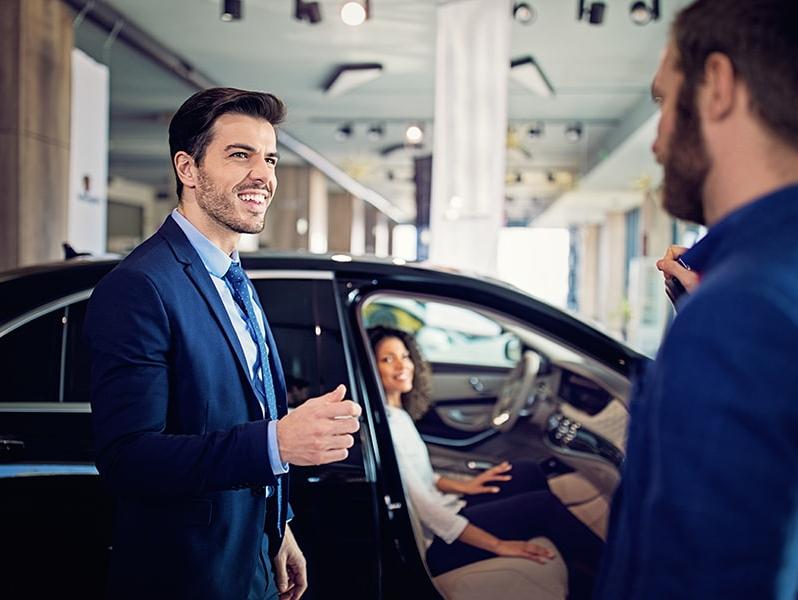 Salesman in a dealership showing a couple a new car