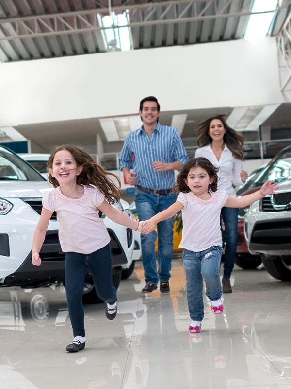 Happy family with children running in a dealership