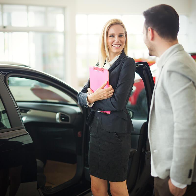 Dealership sales associate showing a customer a new car