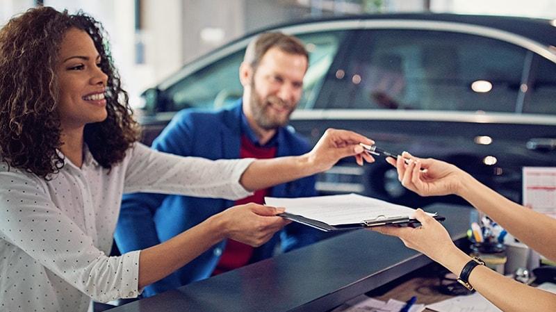 Couple signing finance documents in a dealership