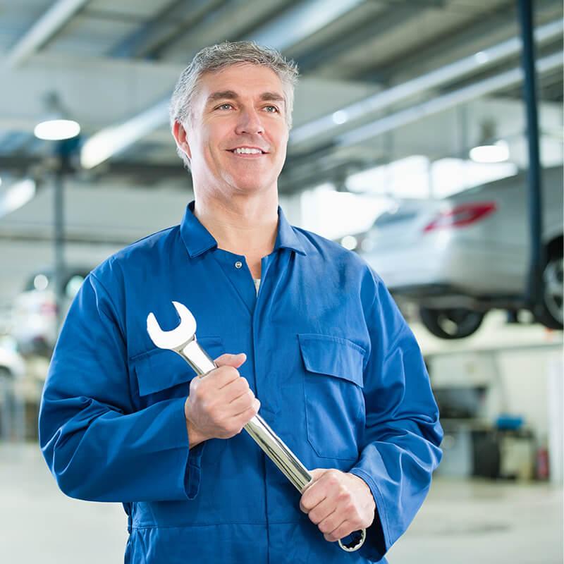 Smiling service mechanic holding a wrench