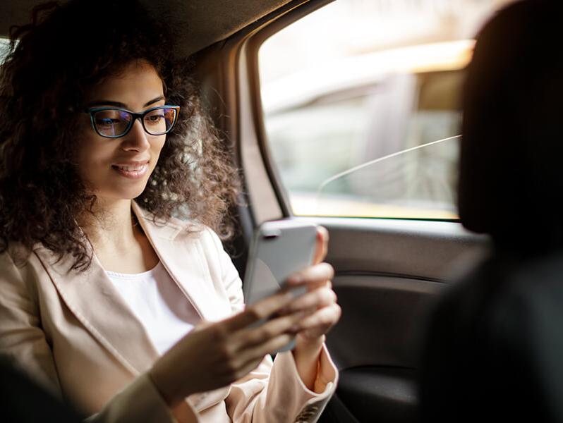 Woman in the backseat of a car using a smart phone