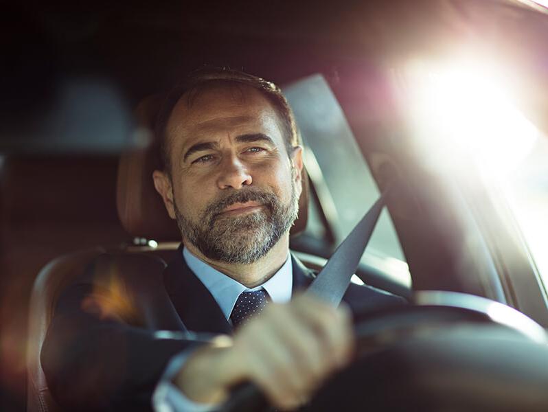 Man in a suit driving a car