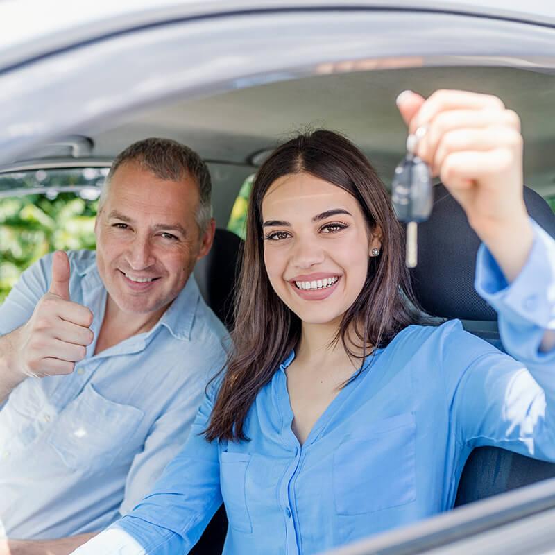Smiling young woman holding up a car key