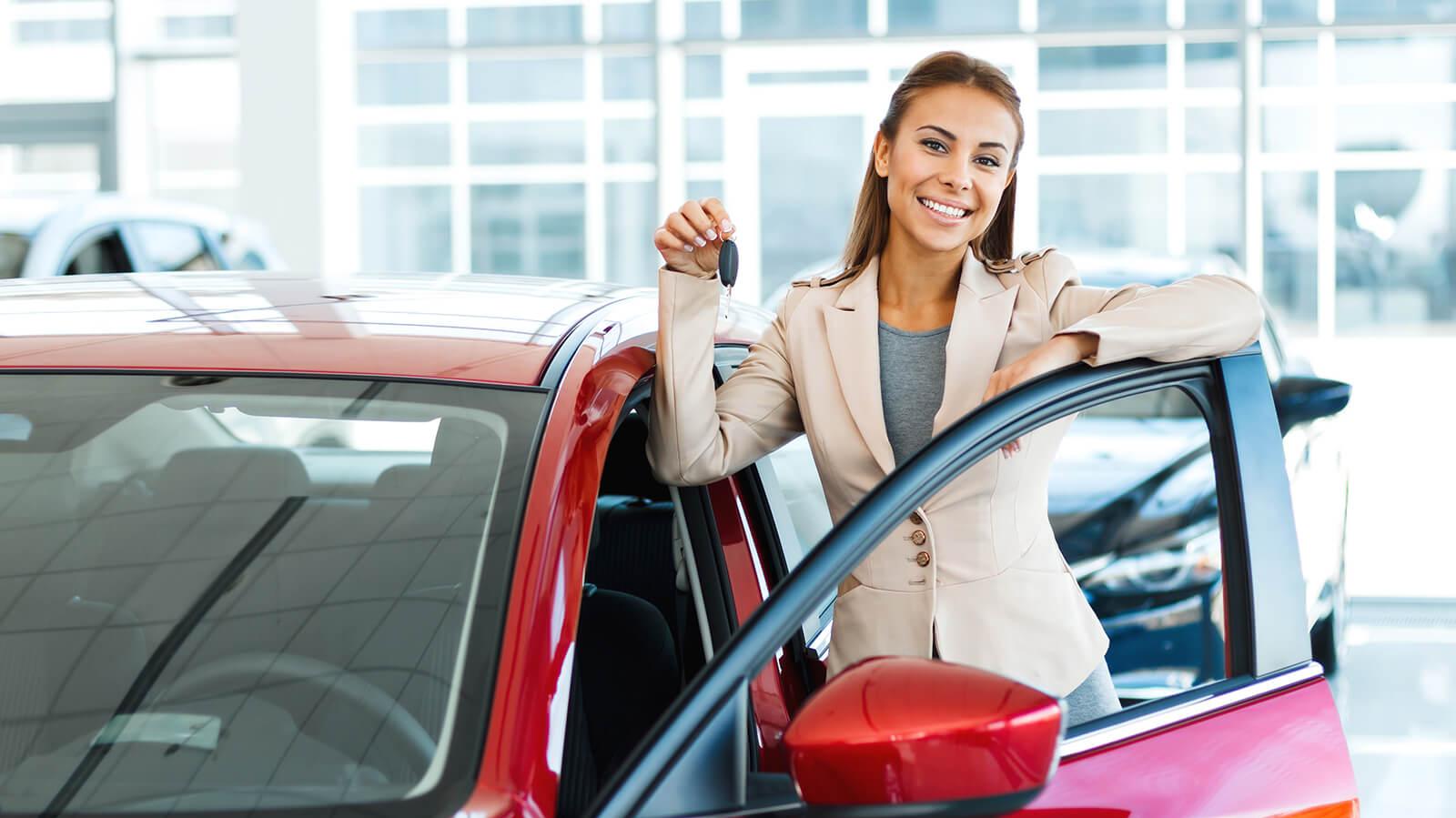 Smiling woman holding keys by a new car