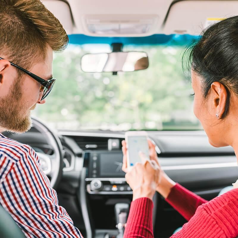 Couple in their car looking at driving directions on a smart phone