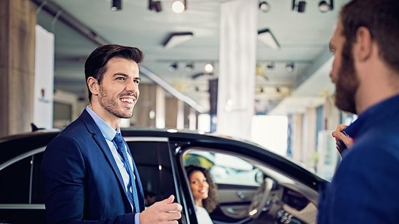 Salesman in a dealership showing a couple a new car