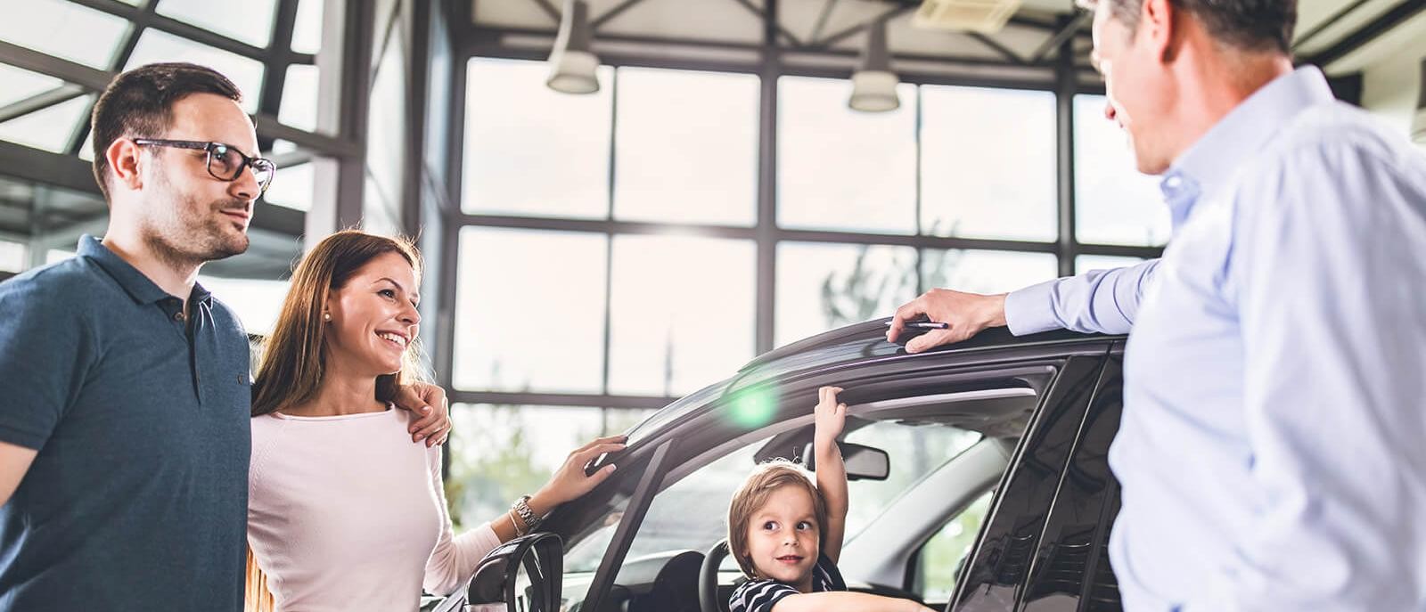 Smiling young family shopping for a new car