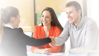 Smiling couple shaking hands with a dealership finance manager