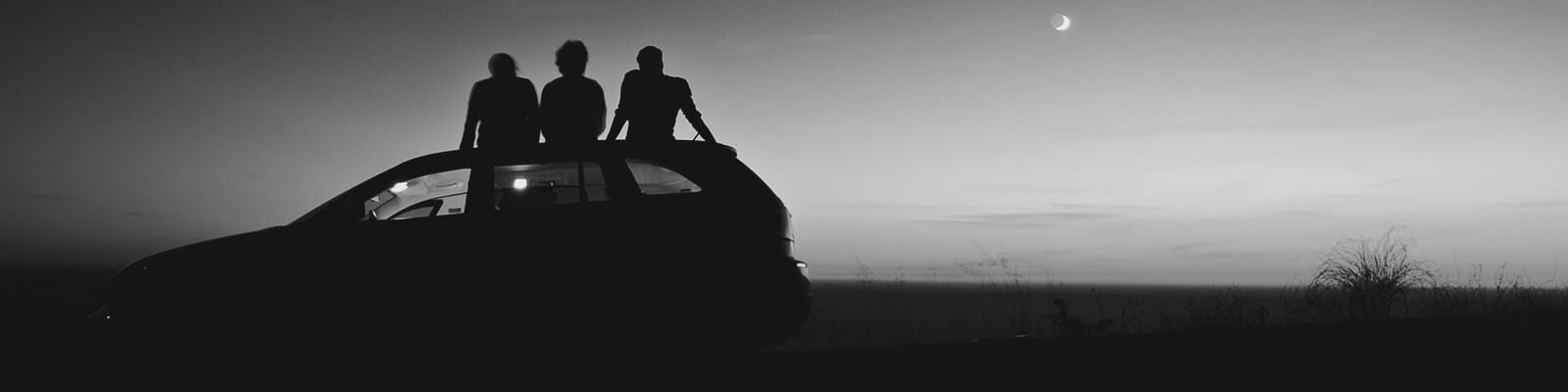 Friends sitting on a car watching the sunset